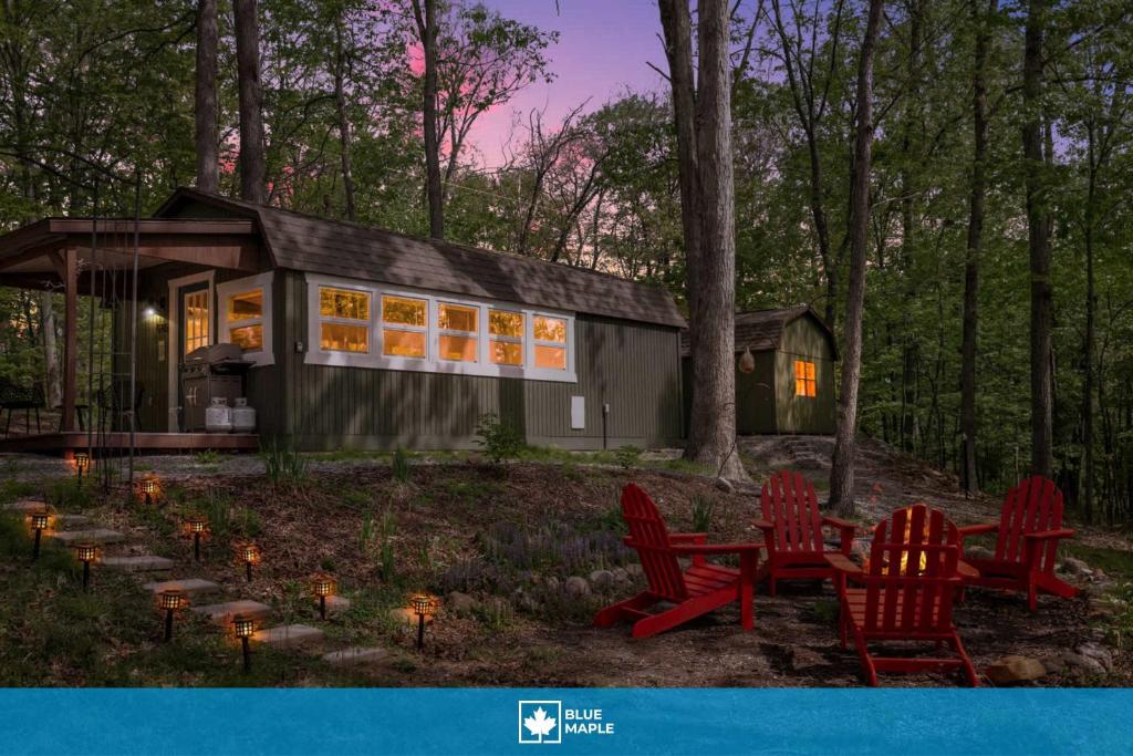 a tiny house in the woods with red chairs and lights at Tiny Cabin w Fire Pit Game Room and Dog Friendly in Great Cacapon