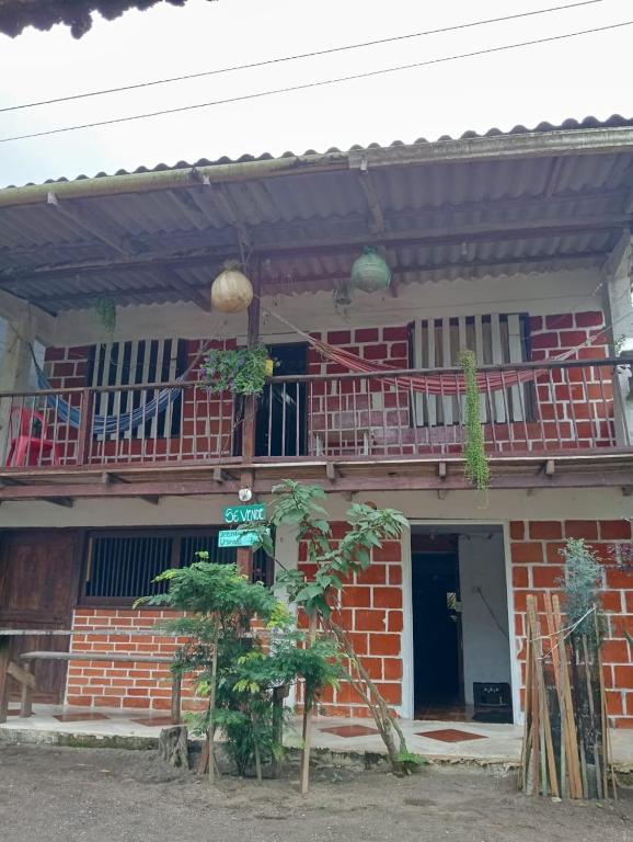 a red brick house with a balcony on top at Posada El Encanto in Nuquí