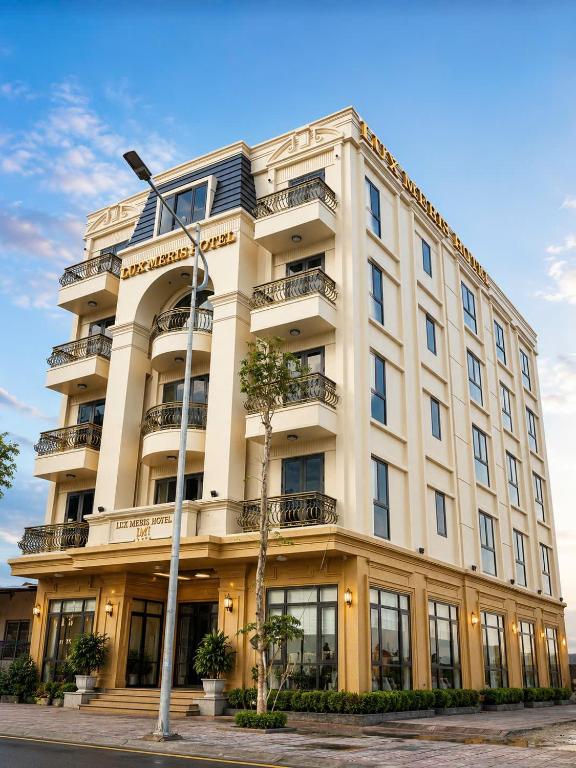 a tall white building with windows and a street light at Lux Meris Hotel in Nhượng Bạn