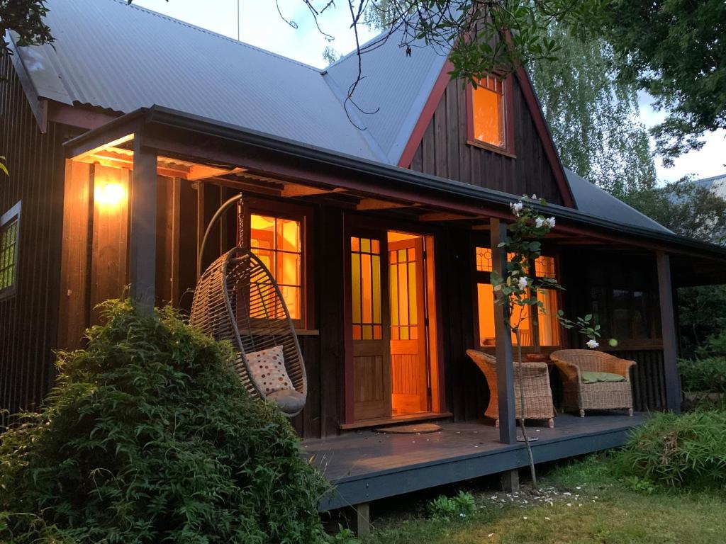 a tiny house with a porch and wicker chairs at Quail Farm, Colonial charm in Nelson