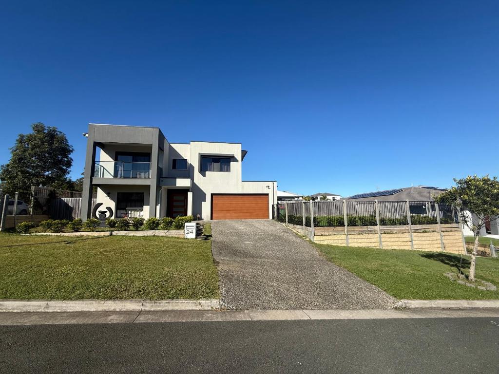 a large white house with a gate and a driveway at Guest House near theme parks in Pimpama
