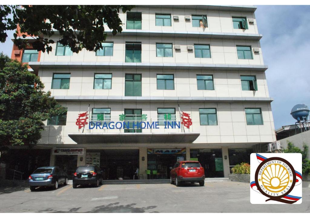 a large white building with cars parked in front of it at Dragon Home Inn in Cebu City