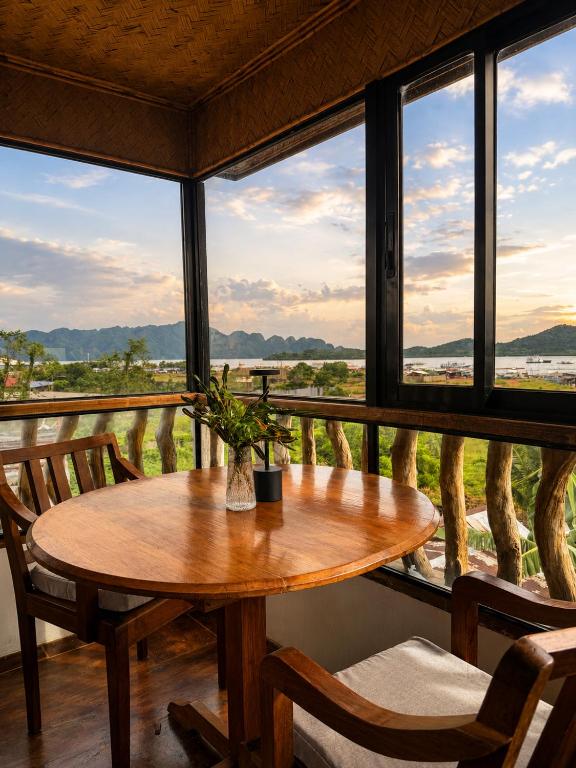 a wooden table and chairs in a room with windows at LIV Coron in Coron