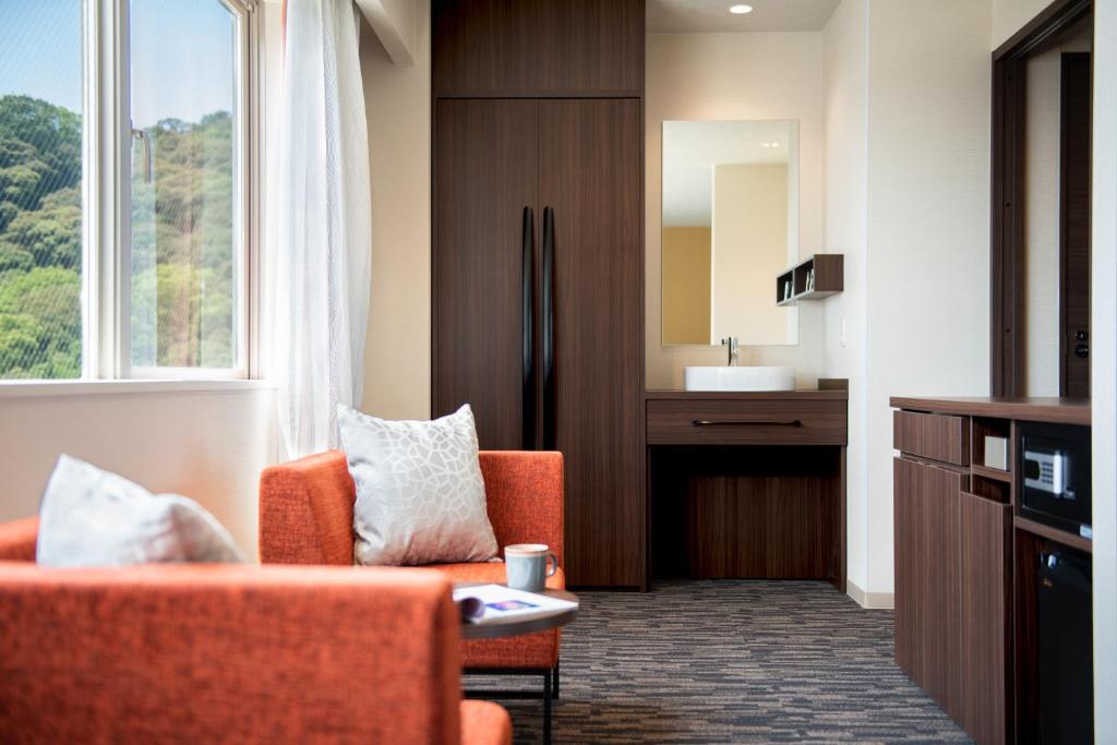 a living room with an orange chair and a sink at Hotel Vista Matsuyama in Matsuyama