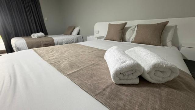 a bedroom with two white beds with towels on them at Jefferys Motel in Toowoomba