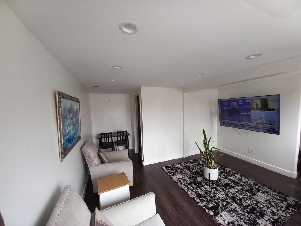 a living room with white furniture and a flat screen tv at Comfort and Cozy stay Free parking on site in Oakland