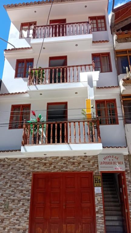 a white building with red doors and a balcony at La Posada del Inca Chavin in Chavín de Huantar