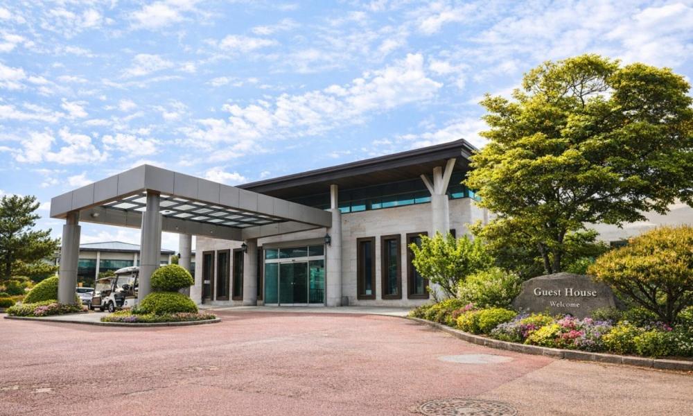 a building with a parking lot in front of it at Jeju Tameus Golf & Village in Hahwajŏn