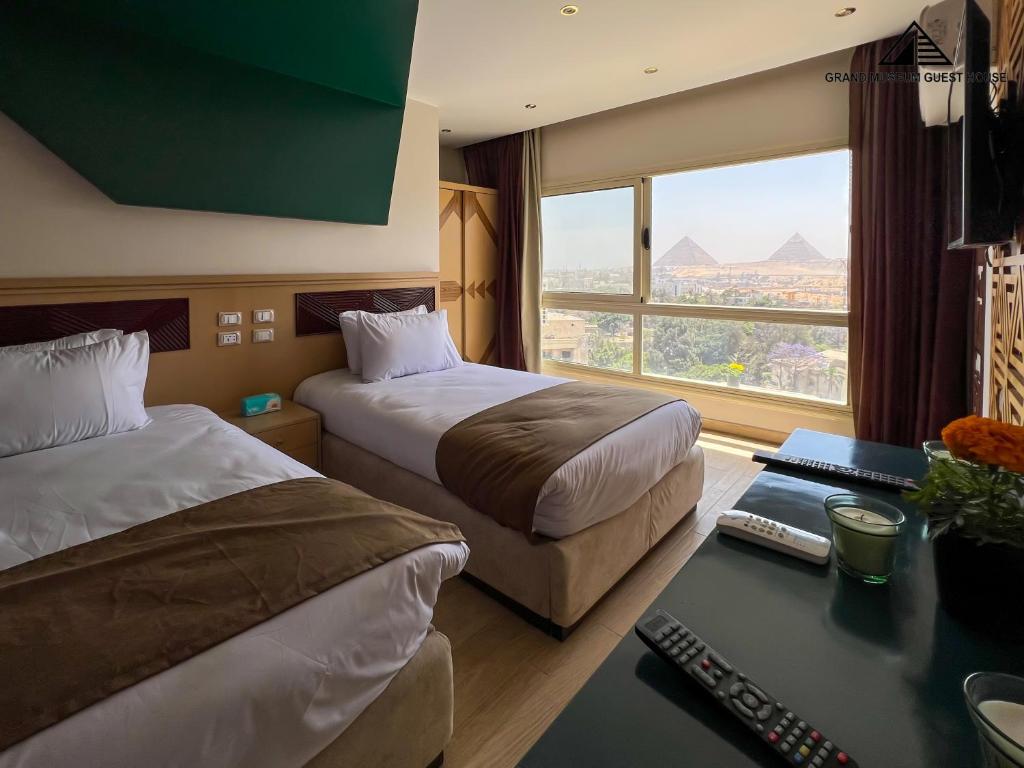 a hotel room with two beds and a desk and a window at Grand Museum with Pyramids view inn in Cairo