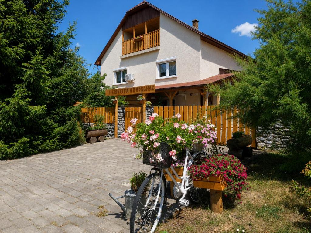 a bike parked in front of a house with flowers at Fenyőfa vendégház in Szilvásvárad