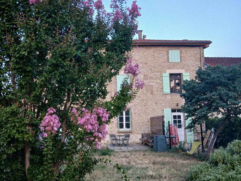 a brick house with pink flowers in front of it at Gîte des collines in Saint-Donat-sur-lʼHerbasse