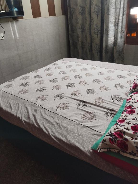 a bed with a white blanket with palm trees on it at Osween Guest House in Srinagar