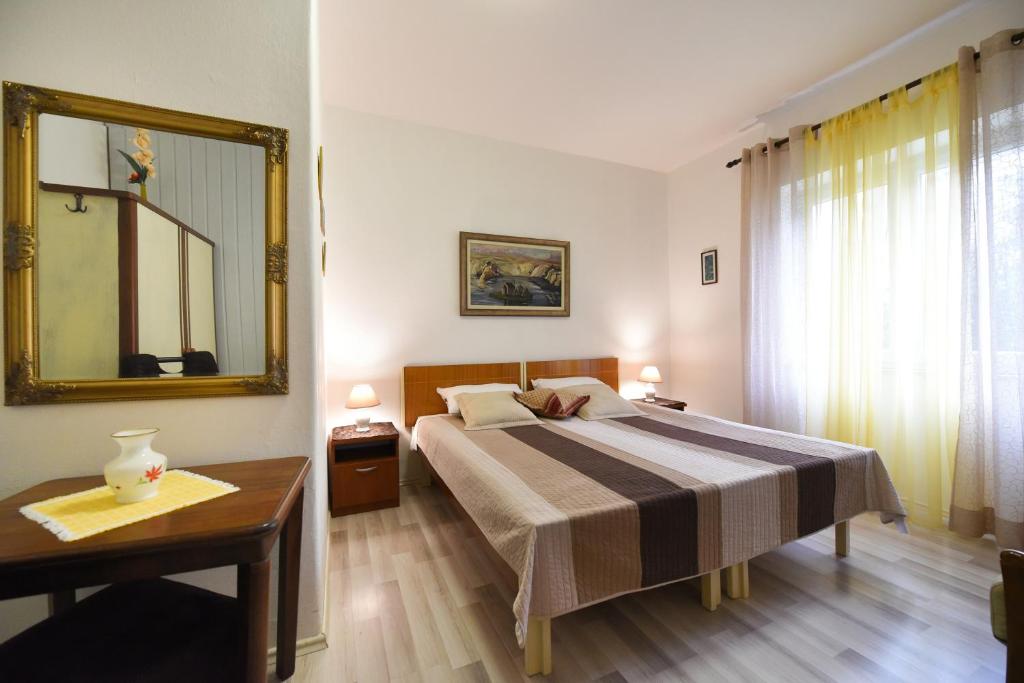 a bedroom with a bed with a mirror and a table at Apartments Dado in Zadar