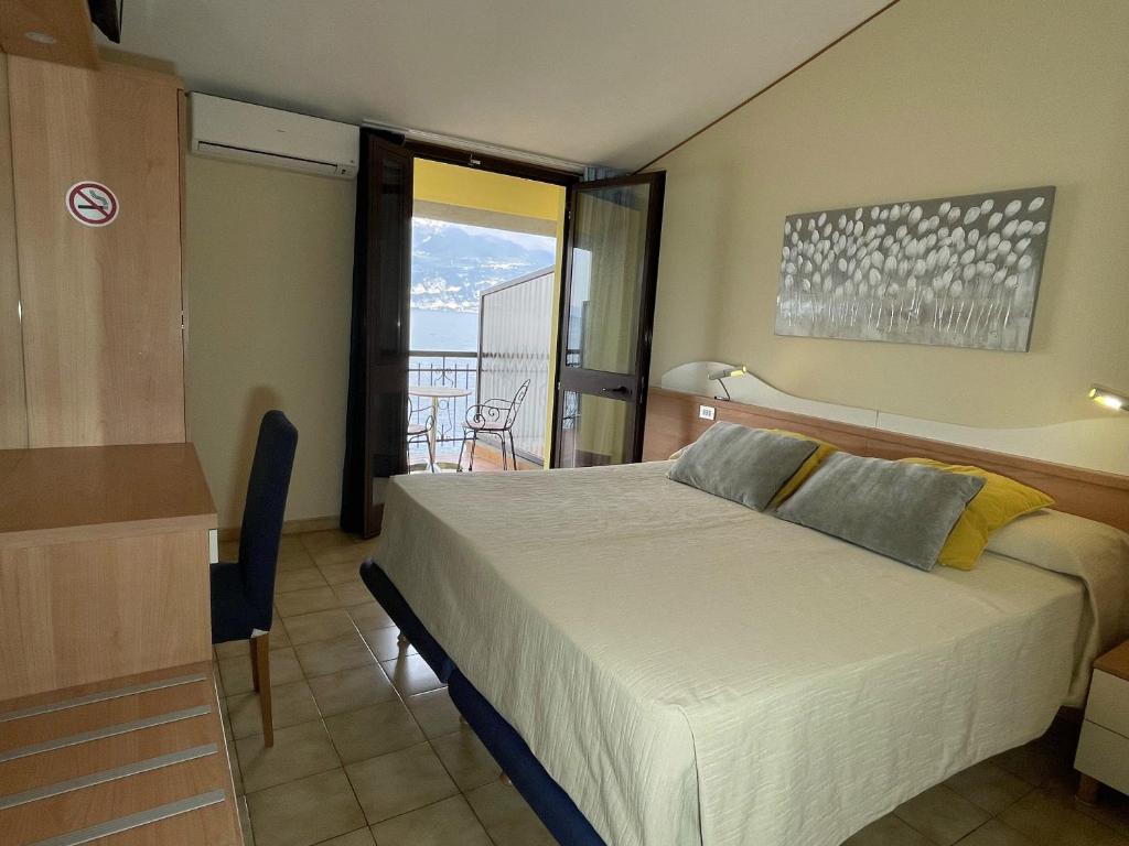 a bedroom with a large bed and a balcony at Taki Village in Brenzone sul Garda