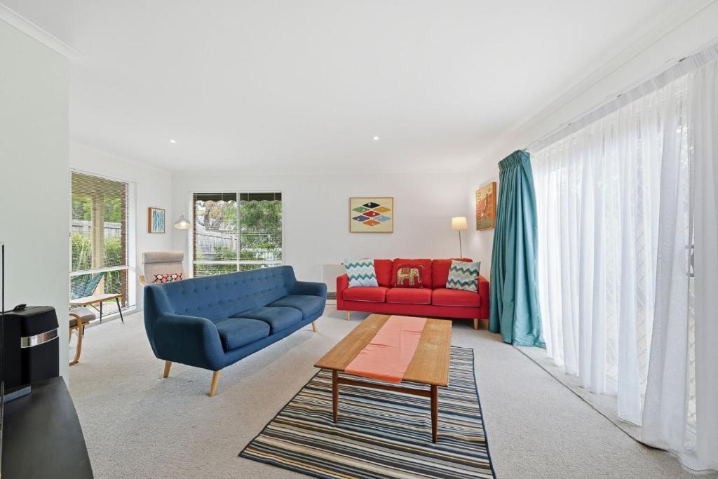 a living room with a blue couch and a red couch at Serrell by the Sea in Inverloch