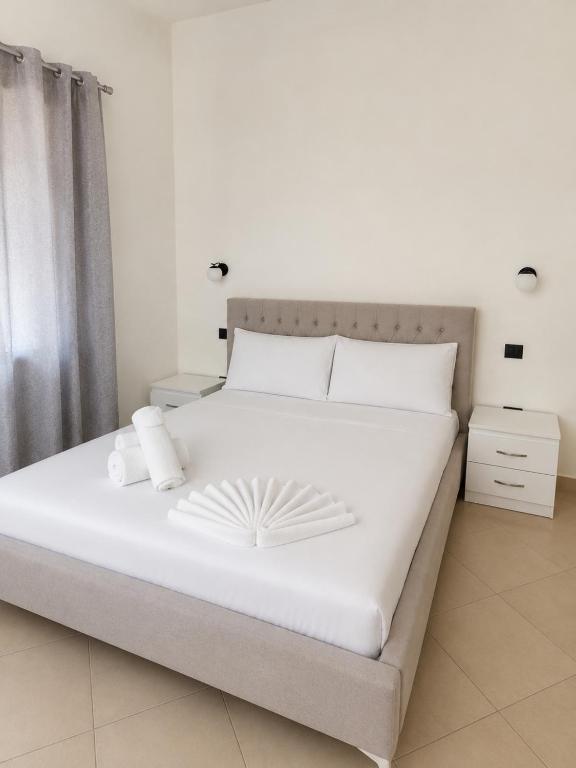 a white bed with white sheets and pillows on it at Rrapi Apartments in Tragjas
