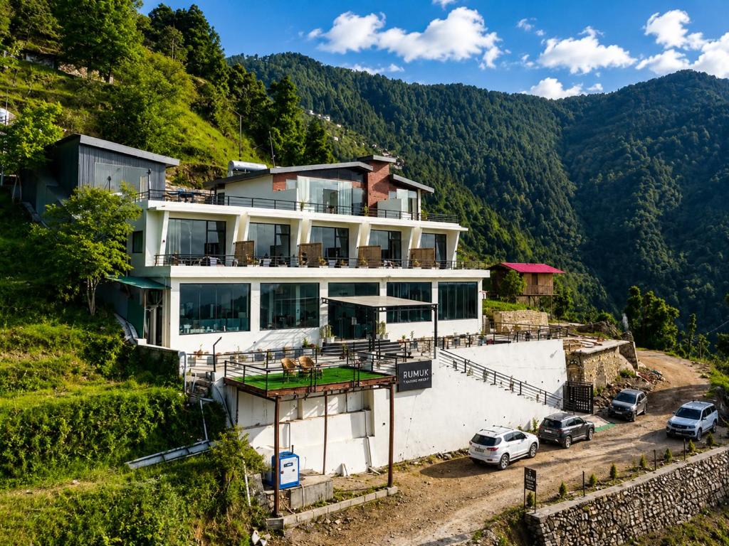 a house on a hill with cars parked in front at Rumuk Boutique Resort - Offbeat escape in Dhanaulti