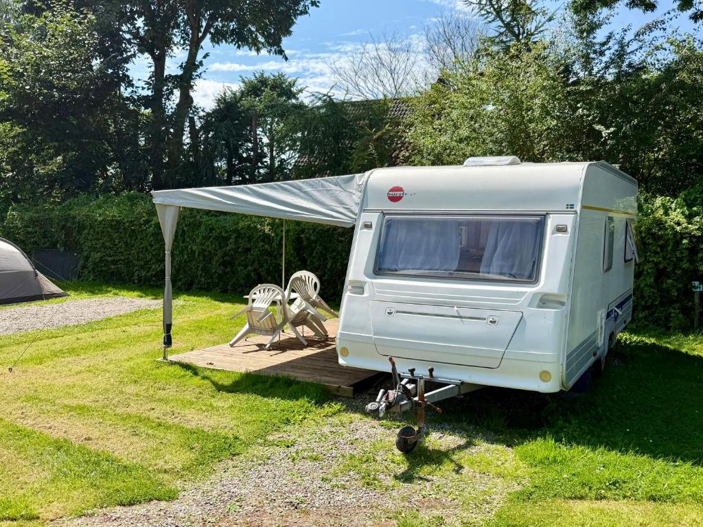 a white trailer parked in a field with a tent at Campinplatz Margarethenruh in Nordstrand
