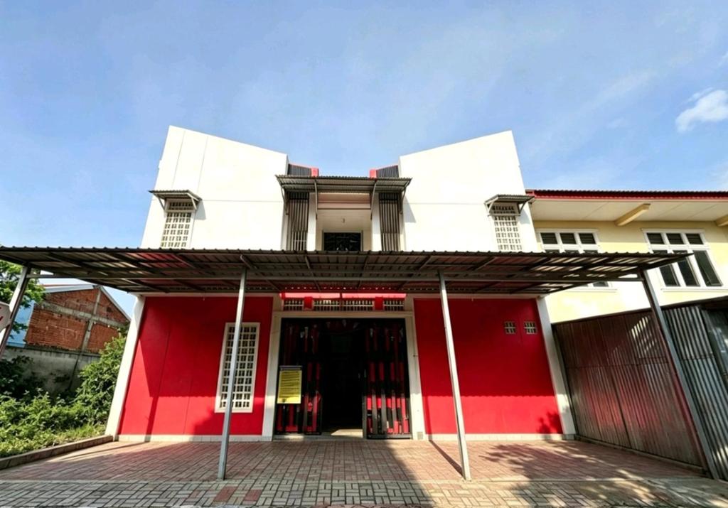 a red and white building with a red door at Hotel O Teratays Homestay in Banda Aceh