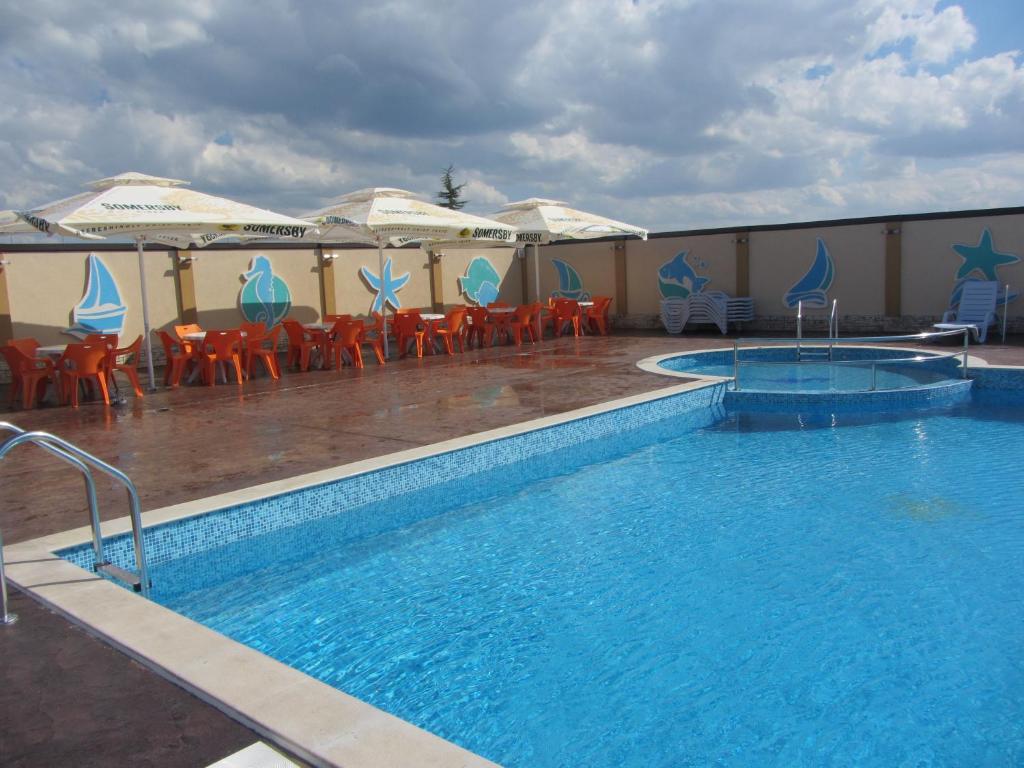 una piscina con mesas, sillas y sombrillas en Hotel Sveti Nikola en Sliven