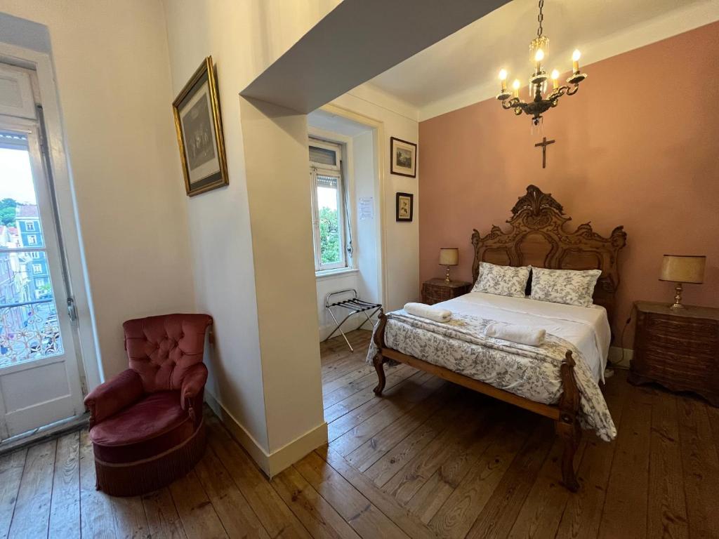 a bedroom with a bed and a chair and a chandelier at Family Macedo in Lisbon