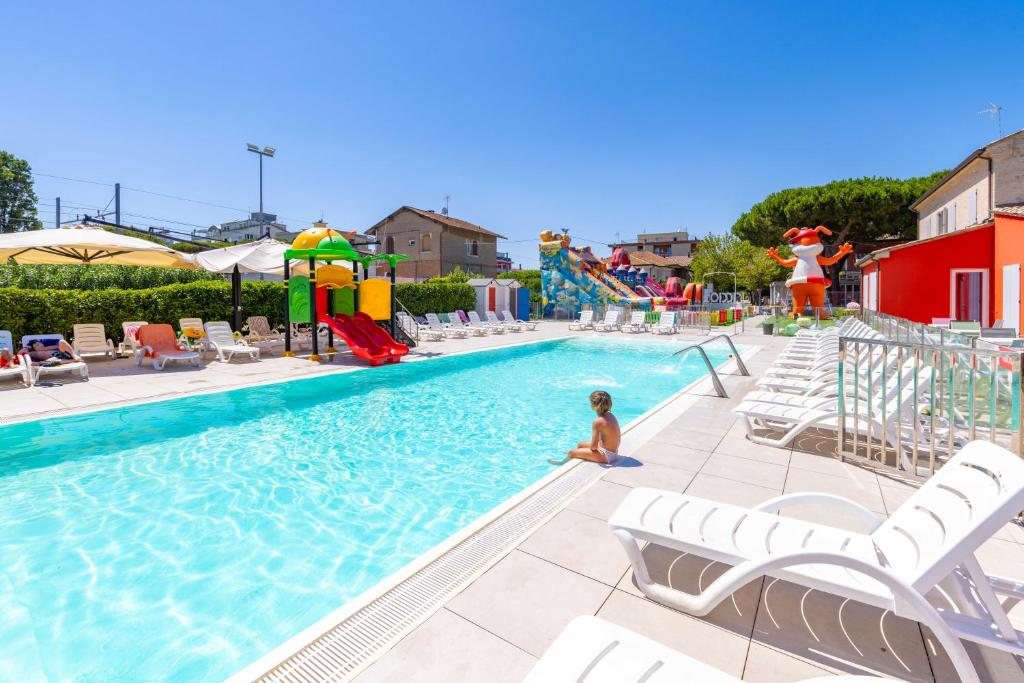 a child sitting in the water in a swimming pool at Ciccio Hotel in Misano Adriatico