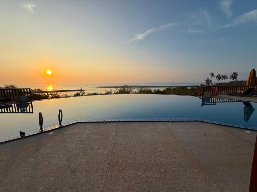 a swimming pool with the sunset in the background at Ananthaya Beach in Tangalle