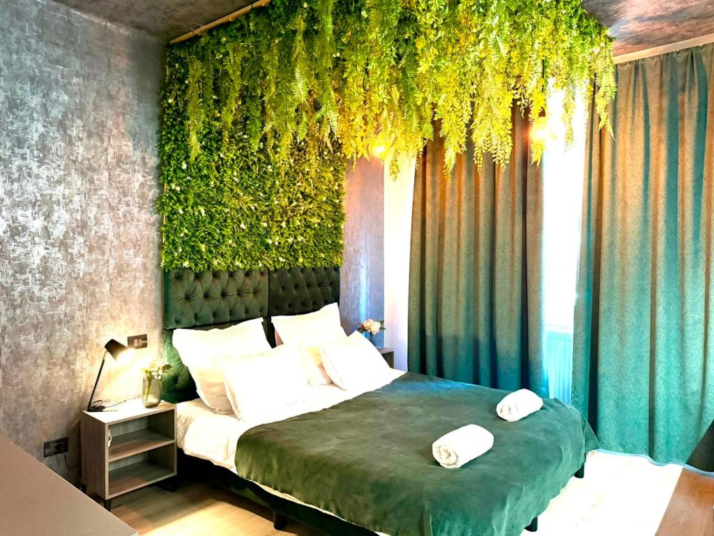 ein Schlafzimmer mit einem Bett und einer grünen Wand mit Pflanzen in der Unterkunft Cozy Hideout - Condo Hotel in Timişoara