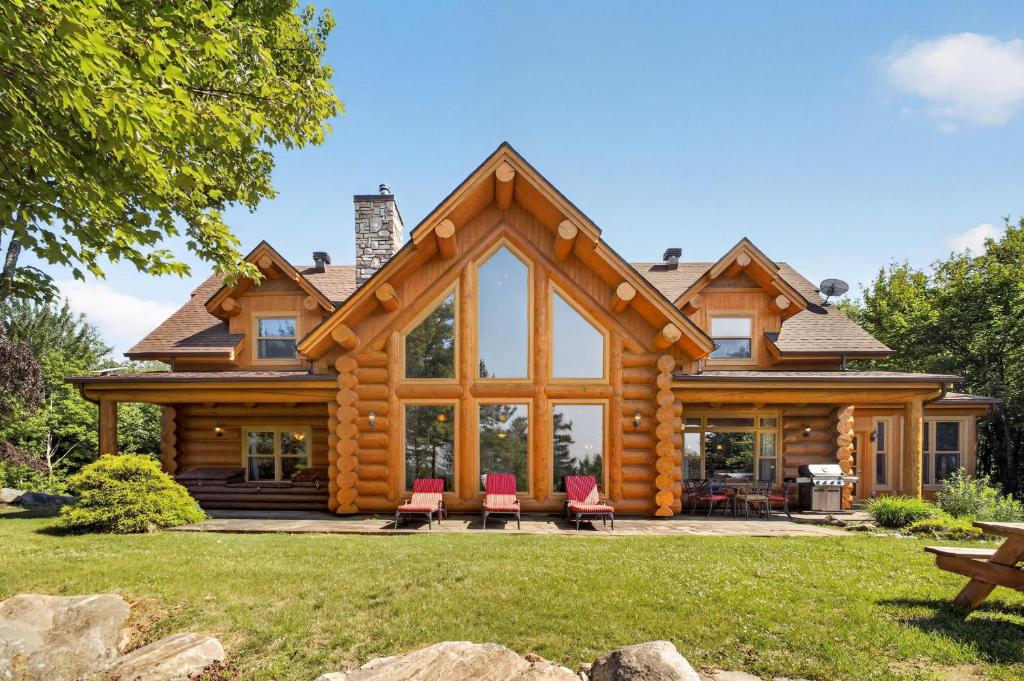 a log cabin with red chairs in the yard at Fiddler Lake Resort - Moose 93 in Mille-Isles