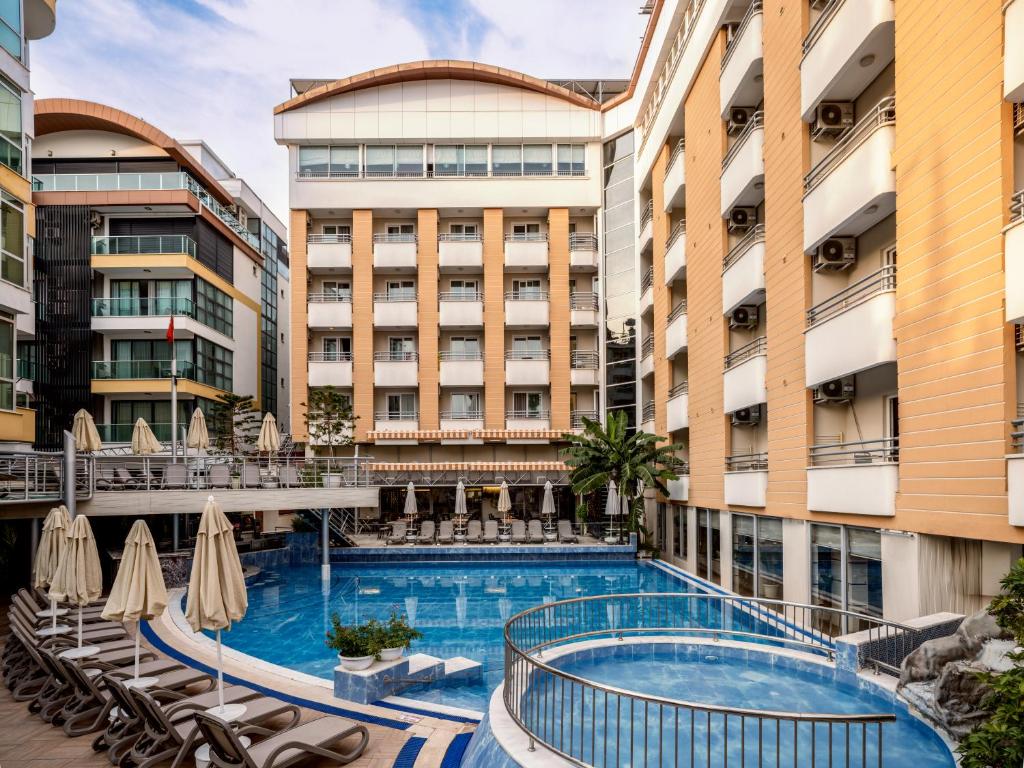 an outdoor pool with chairs and umbrellas in a hotel at Alaiye Kleopatra Hotel in Alanya