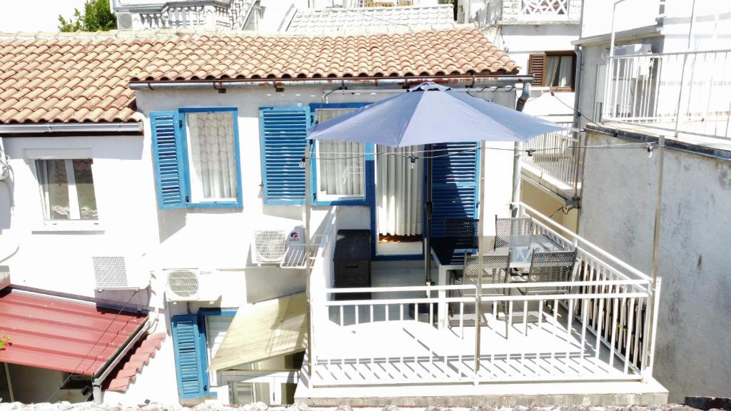 a white house with an umbrella on a balcony at Apartmán Stašica in Selce