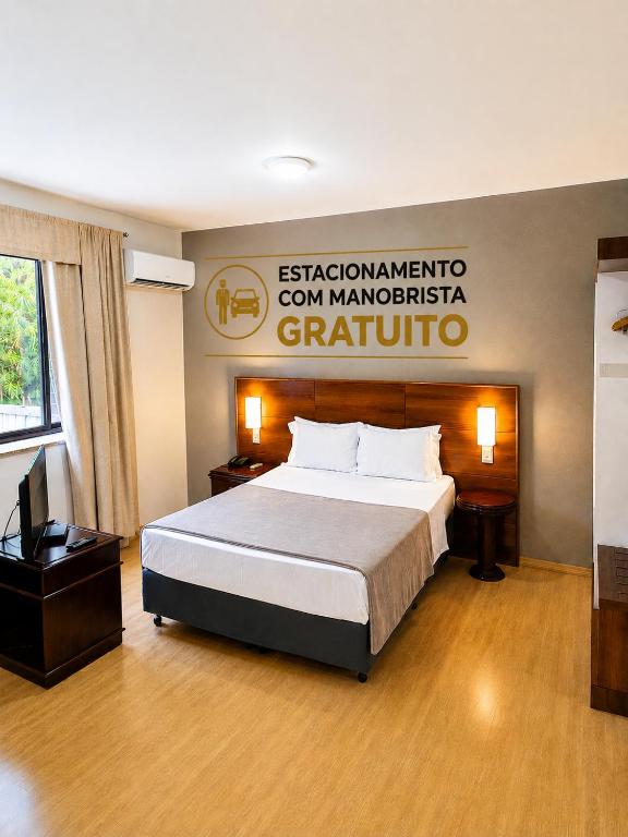 a hotel room with a bed and a sign on the wall at Apartamento no Hotel Prinz in Joinville