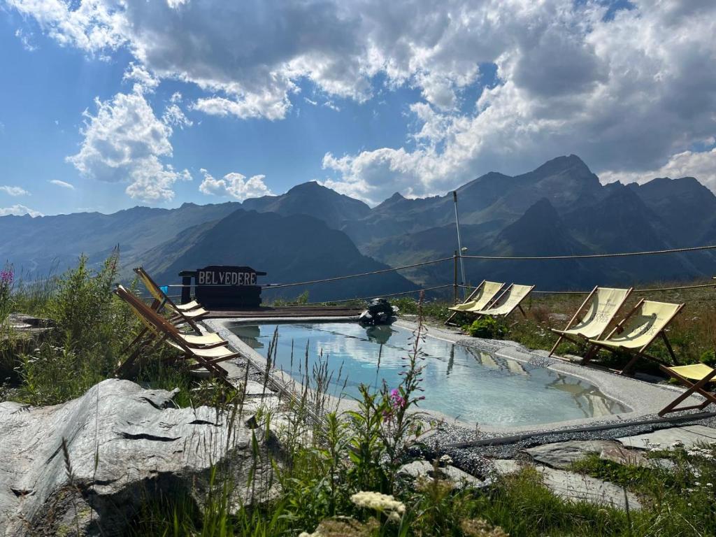 a pool of water with chairs and mountains in the background at Rifugio Baita Belvedere in Champoluc