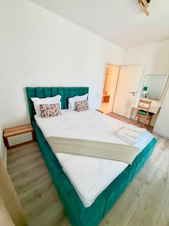 a large bed with a green headboard in a bedroom at DOCA Apartments 8 in Otopeni