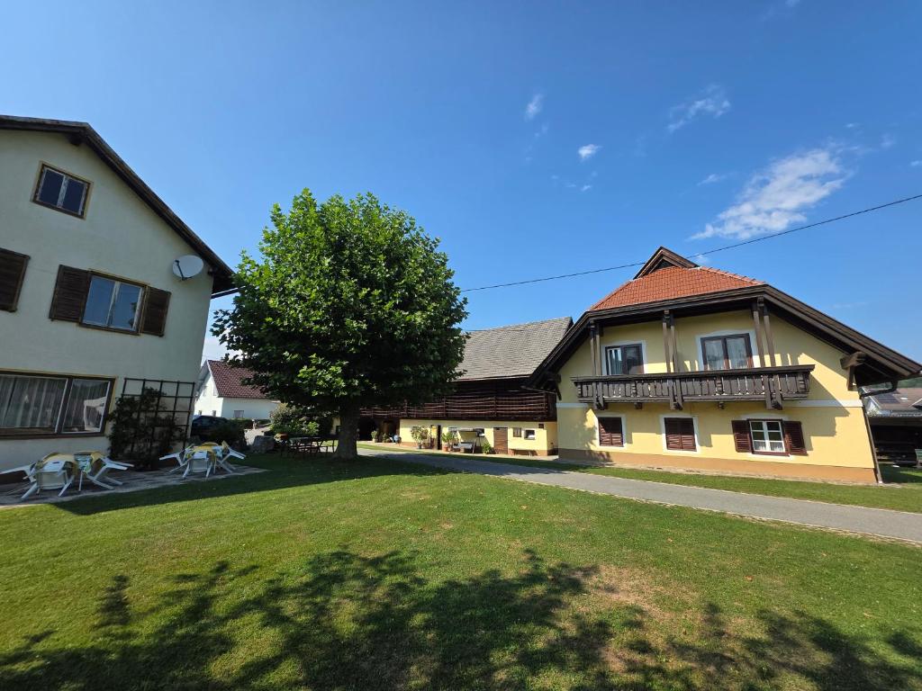 a building with a tree in front of a yard at Gästehaus Dobernig in Sankt Niklas an der Drau