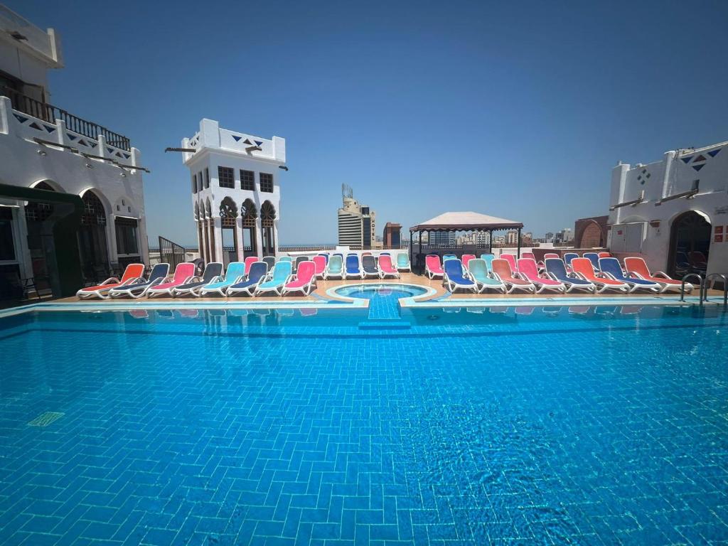 a large swimming pool with lounge chairs and a building at Kuwait Palace Hotel in Kuwait