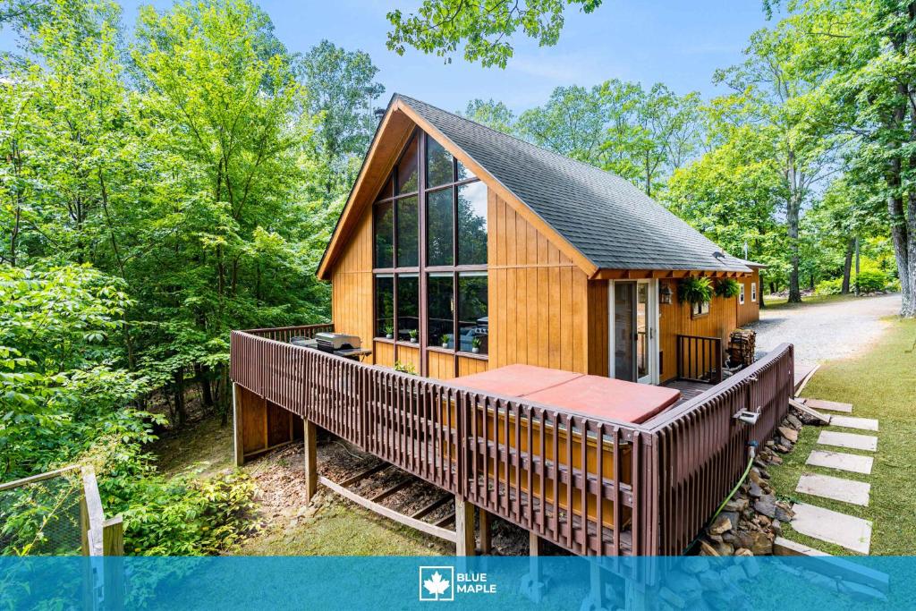 a cabin in the woods with a large window at Quaint Loft Cabin w Hot Tub, FirePit, Deck & Grill in Hedgesville