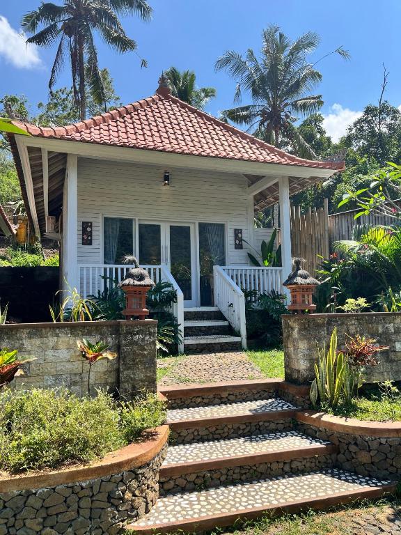 a small white house with a porch and stairs at Bali Dreams Bungalows in Tenganan