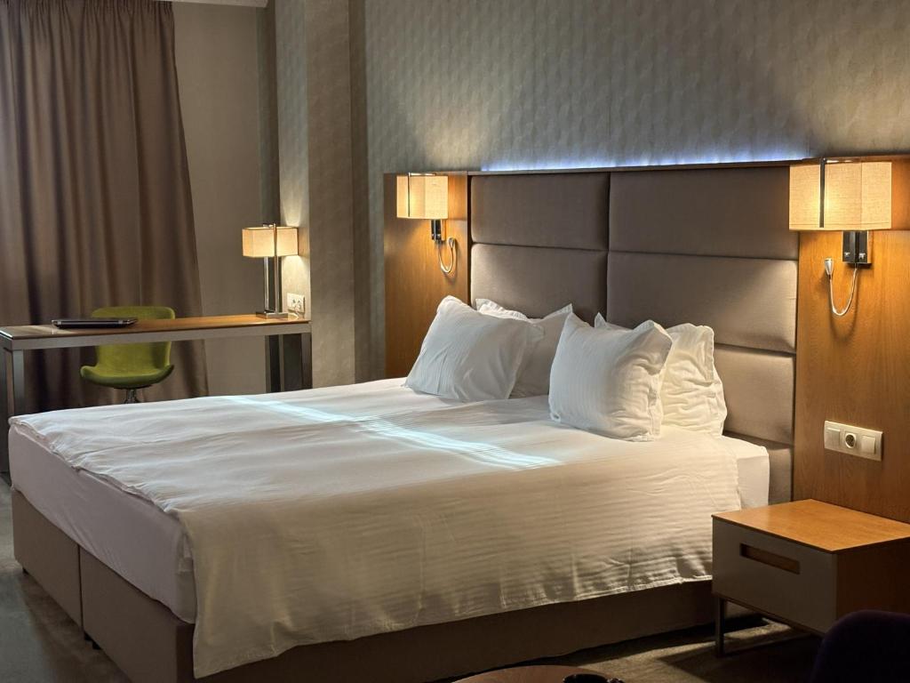 a hotel room with a large bed with white pillows at Hotel Golden Tulip Varna in Varna City
