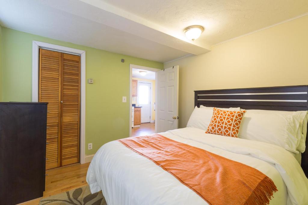 a bedroom with a large bed with an orange pillow at 1 Bedroom Apartments Near Kendall Square in Cambridge