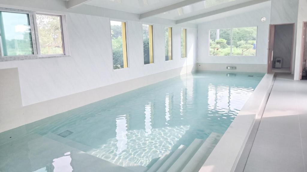 an empty swimming pool with blue water in a white room at Taean Ocean Stay Pension in Taean