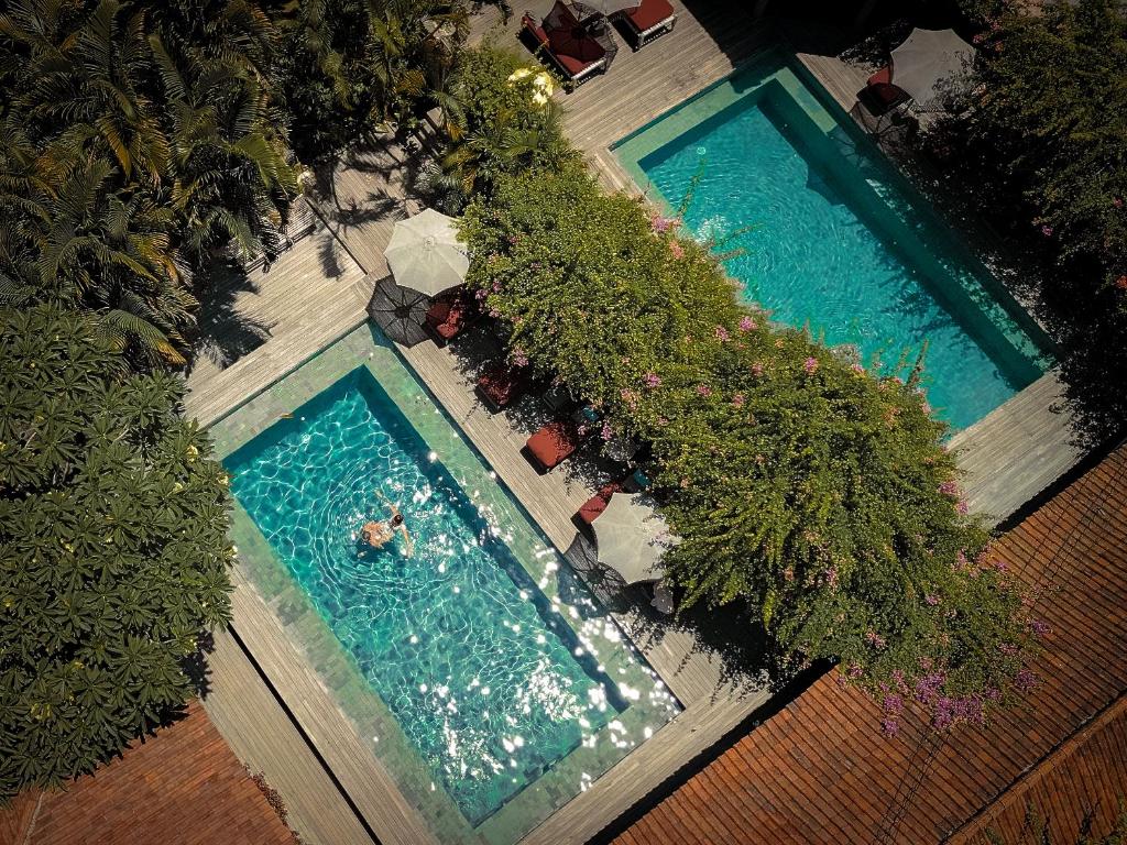 an overhead view of two swimming pools with people in them at Balquisse Heritage Hotel in Jimbaran