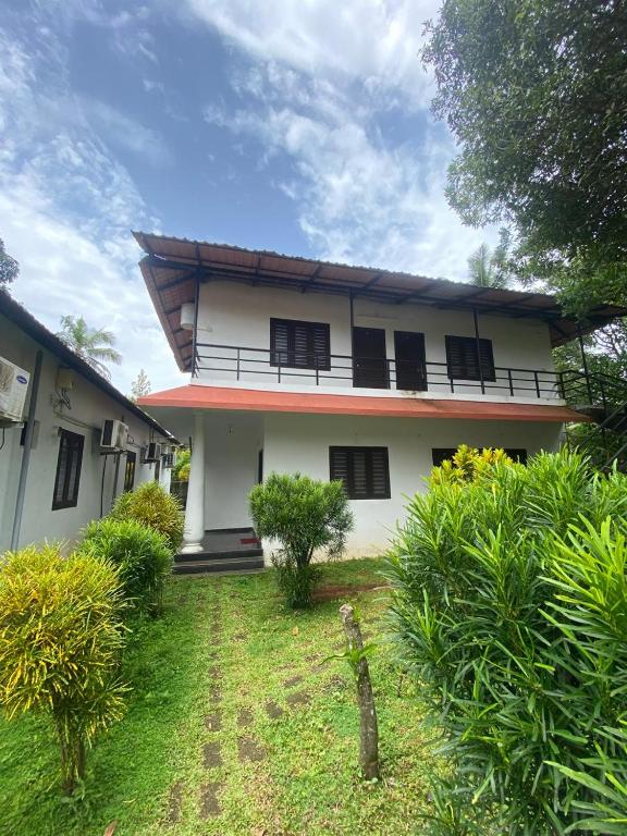 a white house with black windows and a yard at villas alleppey in Alleppey