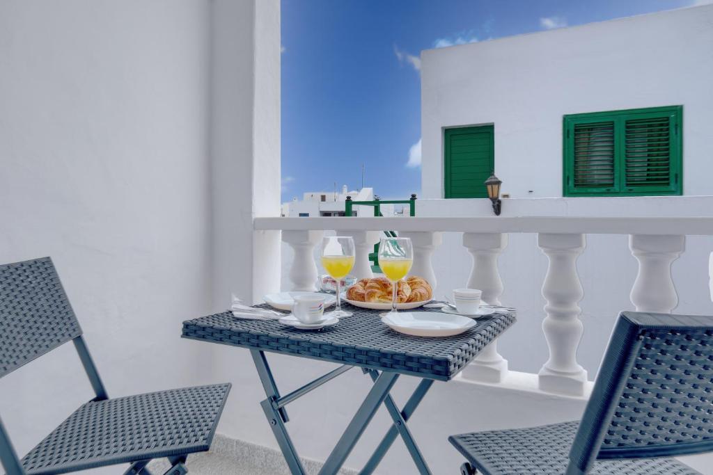 a table with two chairs and two glasses of orange juice at Casa Suso y Casa Margarita- Orzola Coastal Retreat by LVH in Órzola