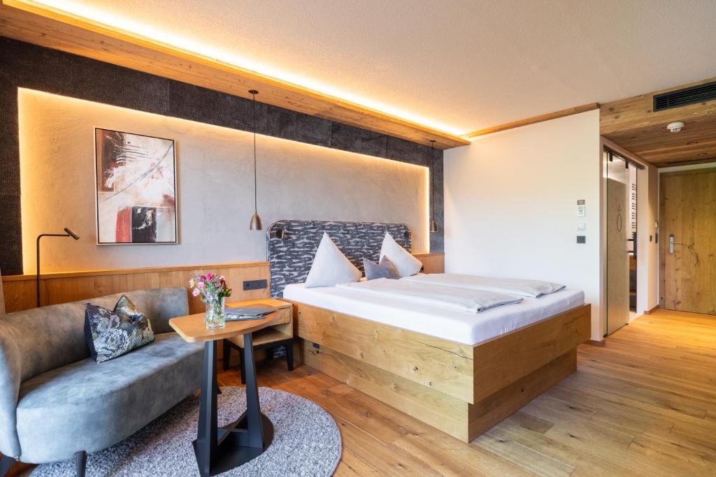 a bedroom with a bed and a couch in a room at Hotel Königgut in Wals