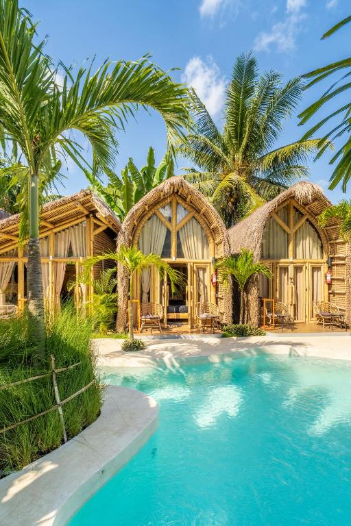 a resort with a swimming pool in front of a house at Mare Eco Bungalows - Kids & Family friendly in Kuta Lombok
