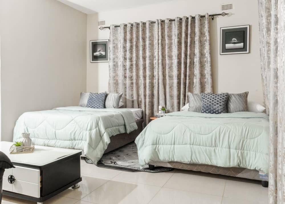 a bedroom with two beds and a window at Lhondeh Apartments in Livingstone