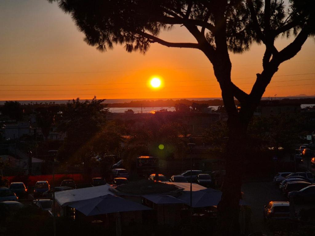a sunset over a parking lot with a tree at Mirabaia in Bacoli
