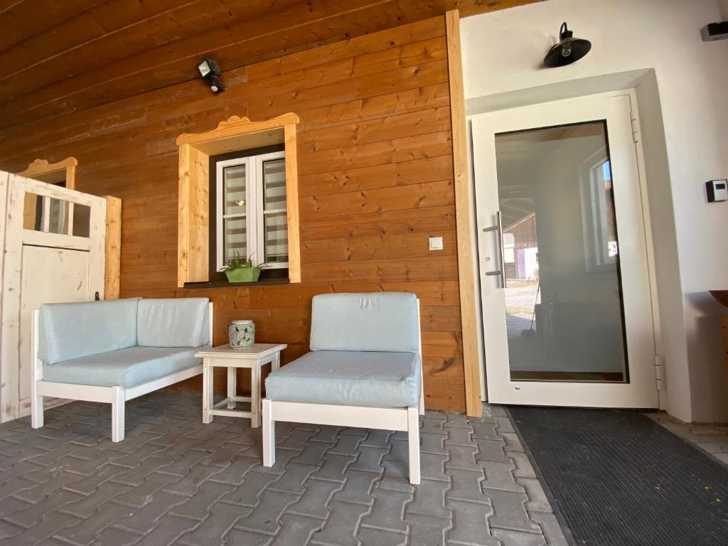 a patio with two chairs and a table and a door at Stodl Living Chiemsee in Grabenstätt