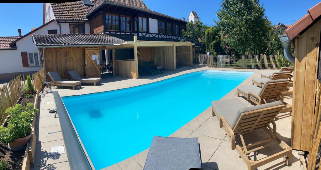 a swimming pool with chairs and a house at Gîte Du Balcon in Diebolsheim